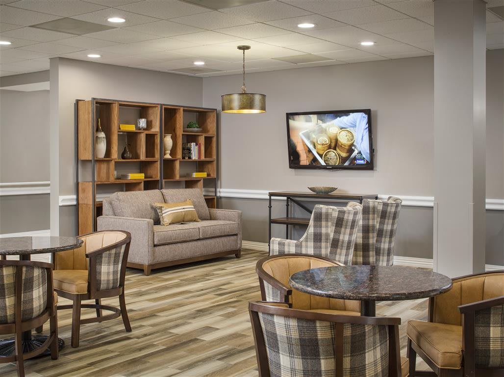 A cozy living room with plaid chairs, a sofa, and a television mounted on the wall.