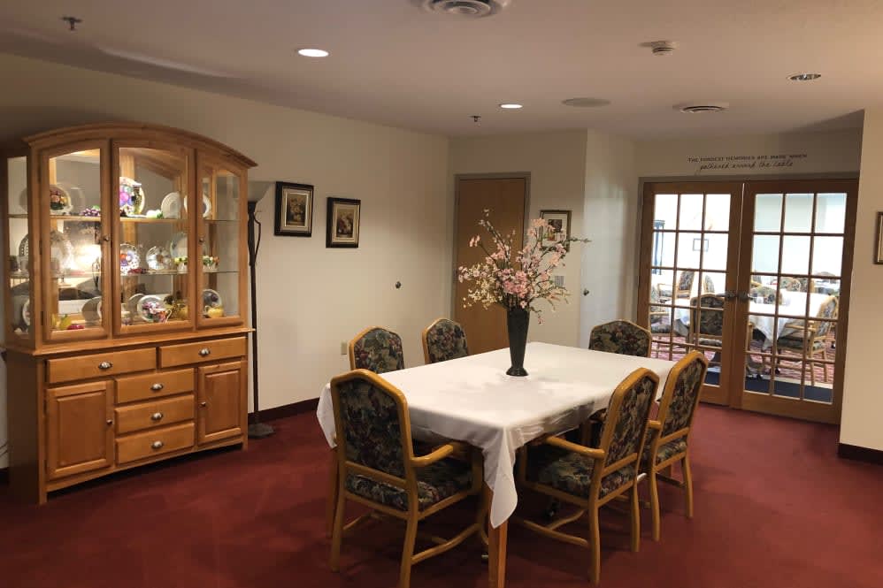 A cozy dining room with a table and chairs, featuring a decorative vase on a white tablecloth.