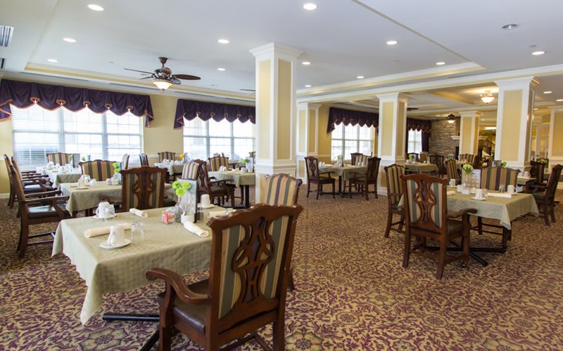 An elegant dining room with multiple tables and chairs arranged on a carpeted floor.