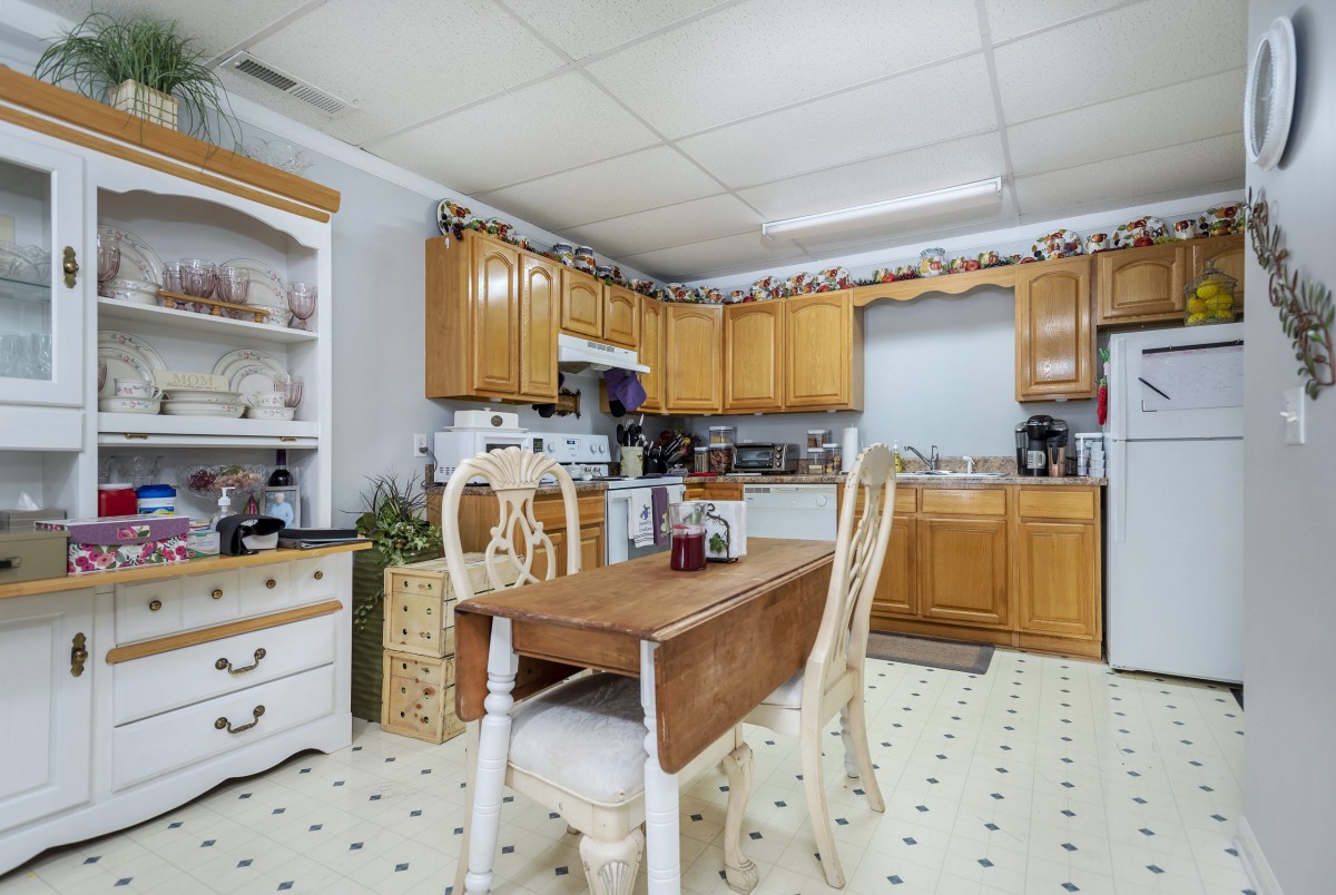 A cozy kitchen with wooden cabinets, a small dining table, and various kitchen appliances.