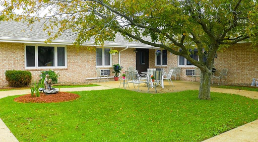 A charming house with a well-kept lawn and patio area, surrounded by trees.