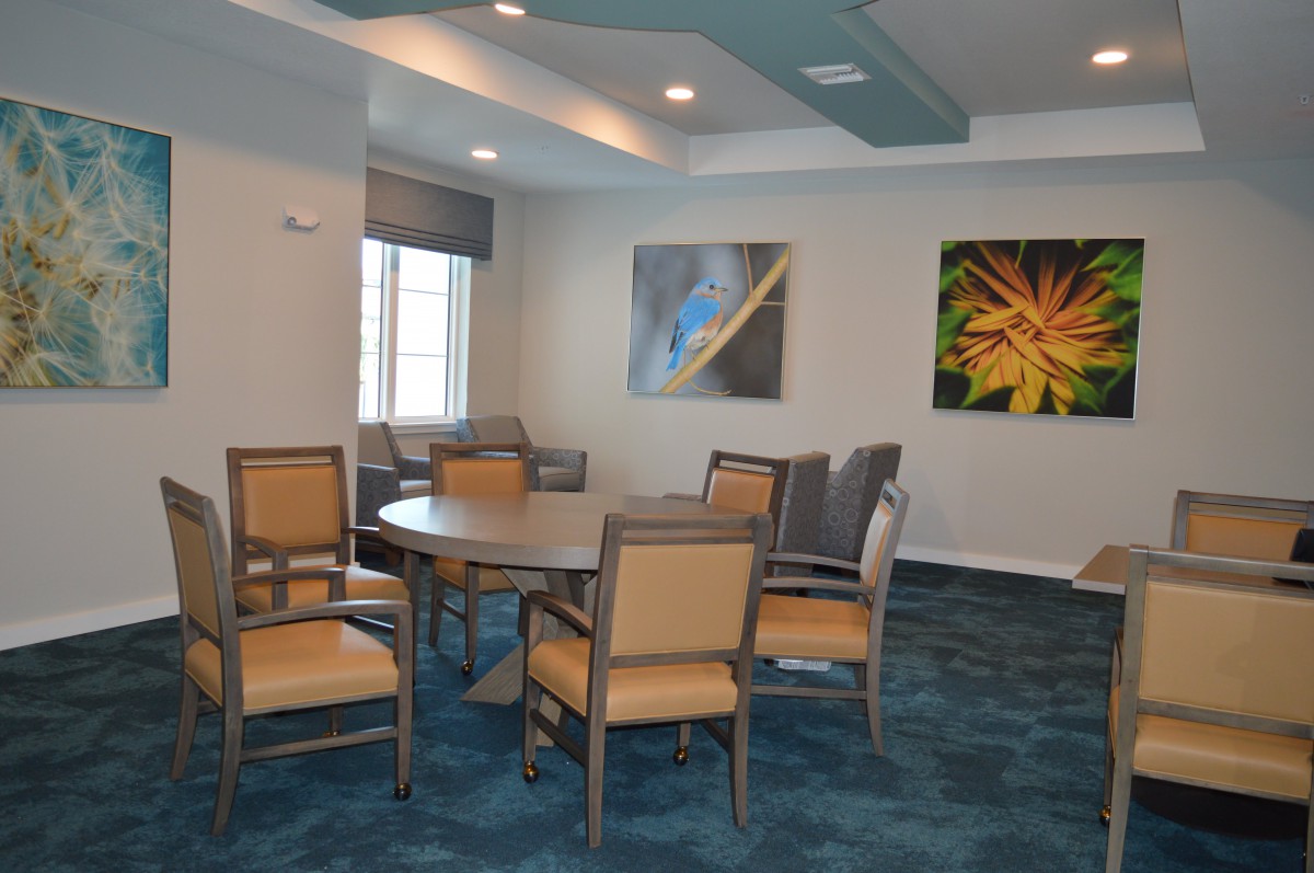 A dining room with a round table, several chairs, and artwork on the walls.