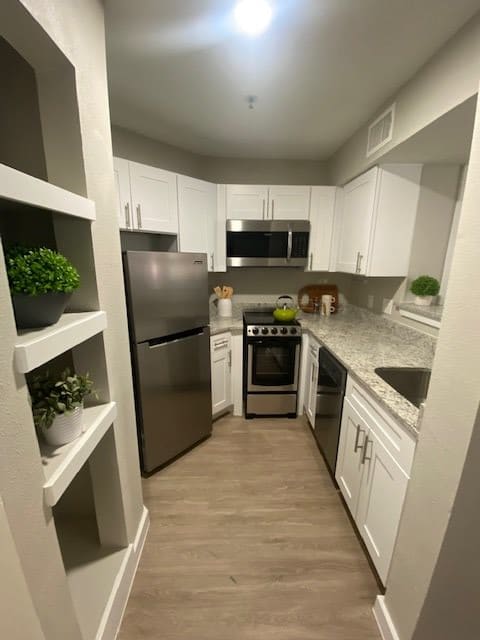 A modern kitchen with stainless steel appliances and white cabinetry.