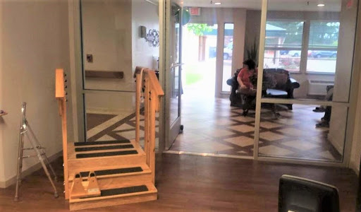 A view of a modern indoor space featuring a staircase leading to a lounge area, with glass doors providing access to an outdoor environment.