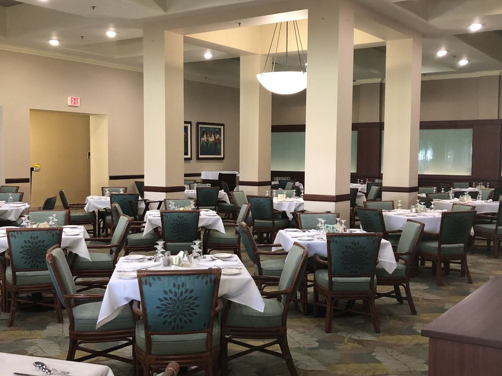 An empty restaurant dining room with neatly arranged tables and chairs.
