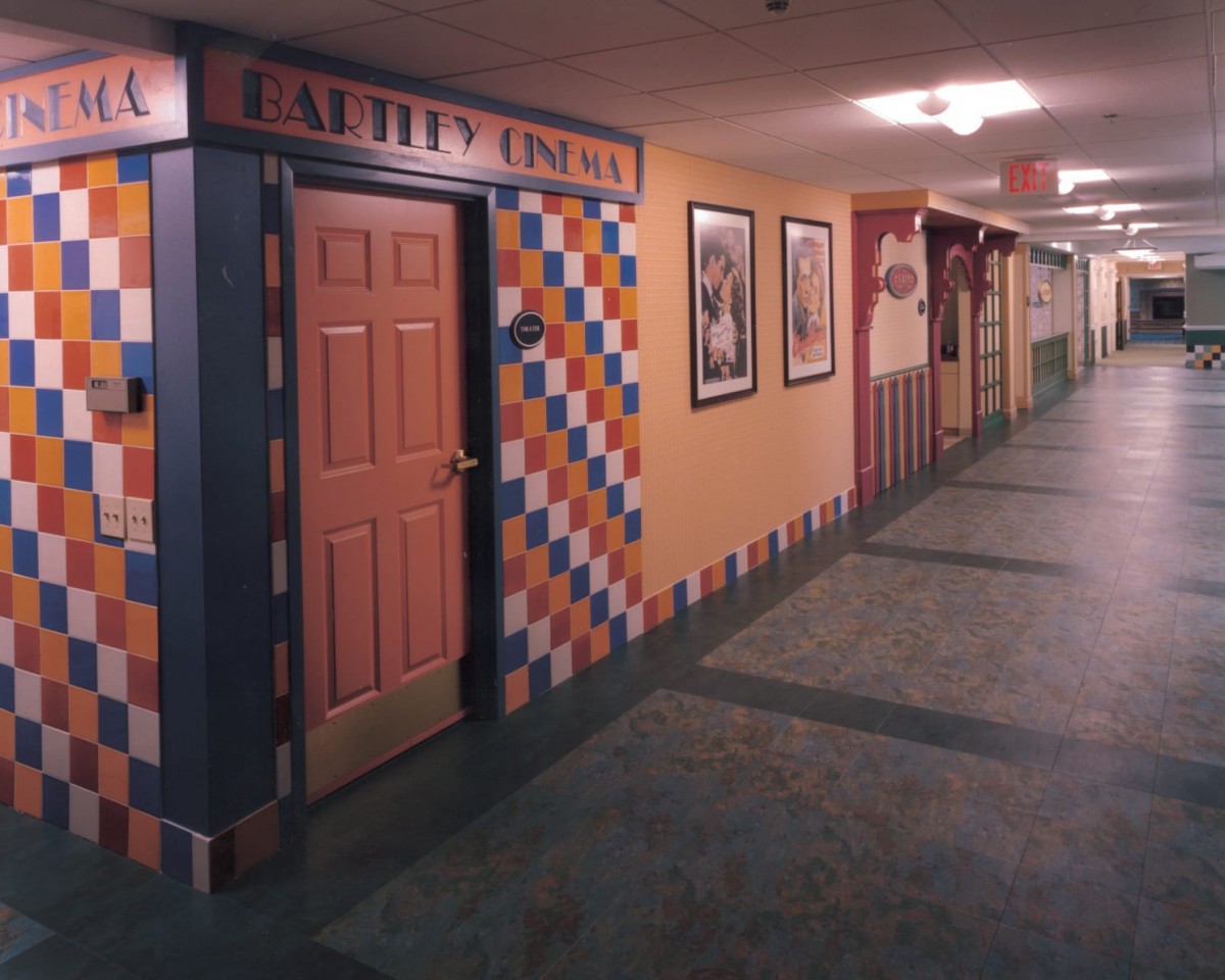 A colorful hallway with multiple doors and tiled wall decorations, resembling a hotel or themed corridor.