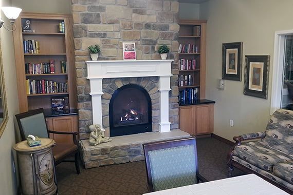 A cozy living room with a stone fireplace and bookshelves.