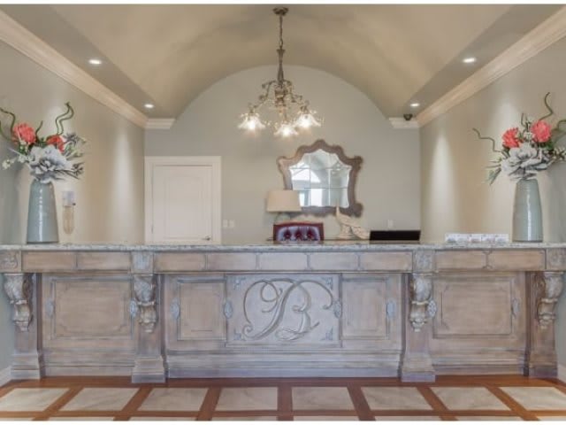 An elegantly designed reception area featuring a decorative desk and chandelier.