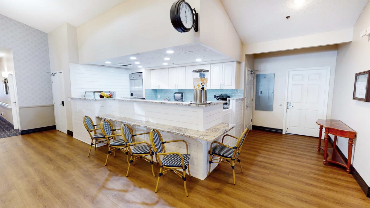 A modern kitchen area with bar seating and bright lighting.