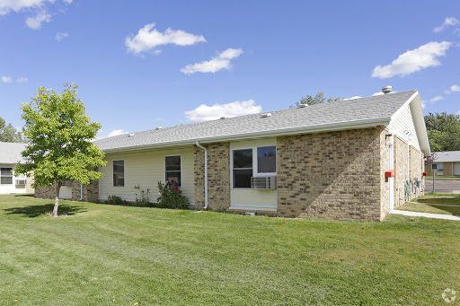 A charming single-story house surrounded by lush green grass and a clear blue sky.