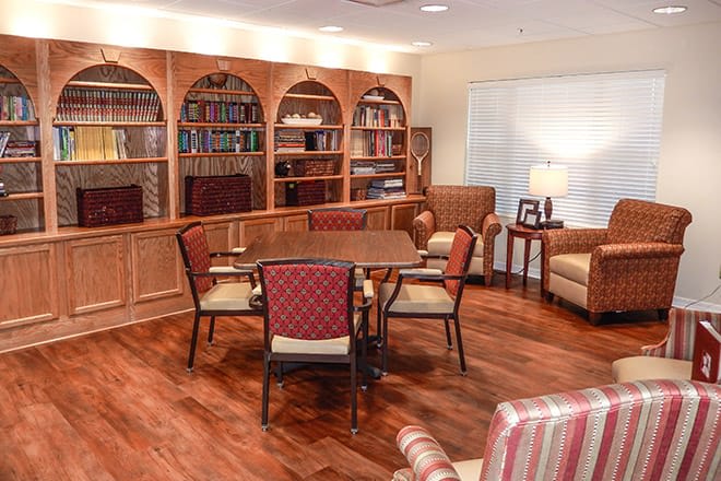 A cozy library with wooden bookshelves and a table surrounded by chairs.