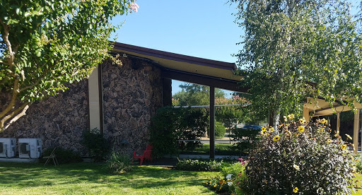 A modern house with stone exterior and lush garden on a sunny day.