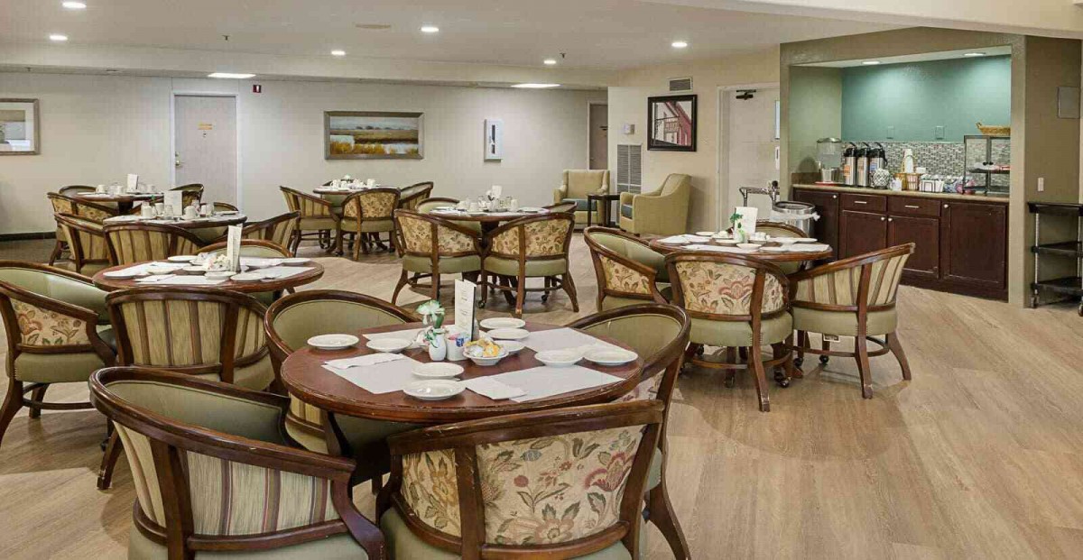 A cozy dining room with elegantly set tables and comfortable chairs, featuring wooden furniture and decor.