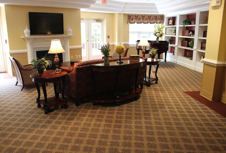 A cozy living room space with elegant furniture, a piano, and bookshelves.