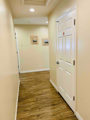 A view of a well-lit hallway featuring wooden flooring and decorative paintings on the walls.