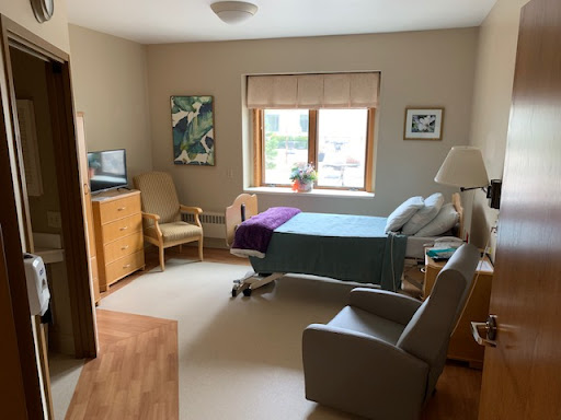 A well-lit hospital room designed for patient comfort, featuring a hospital bed, seating area, and window.