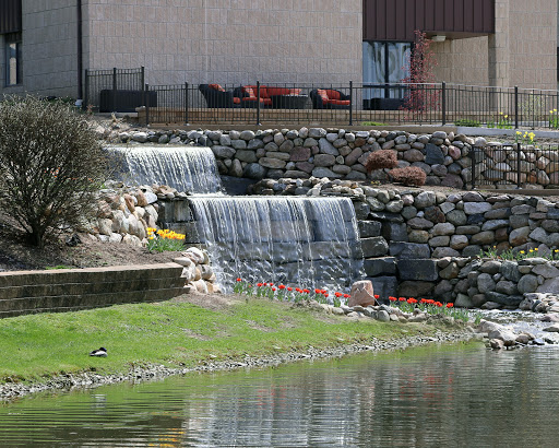 A serene view of a cascading waterfall surrounded by lush greenery and stone features.
