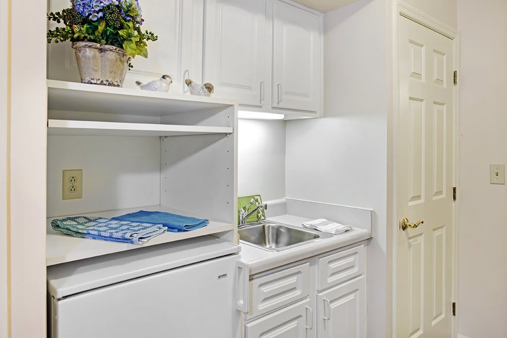 A clean and minimalist laundry room with white cabinets and a sink.