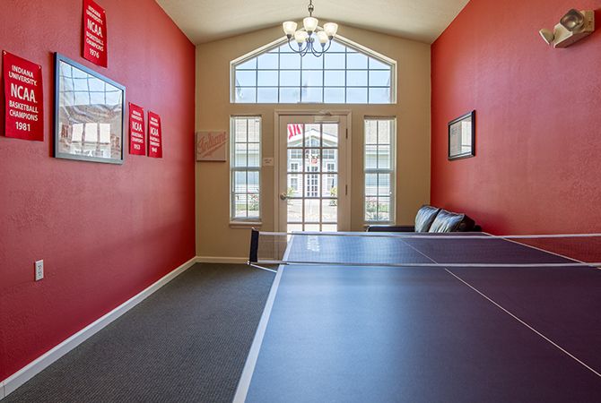 A bright and inviting game room featuring a ping pong table and large windows.