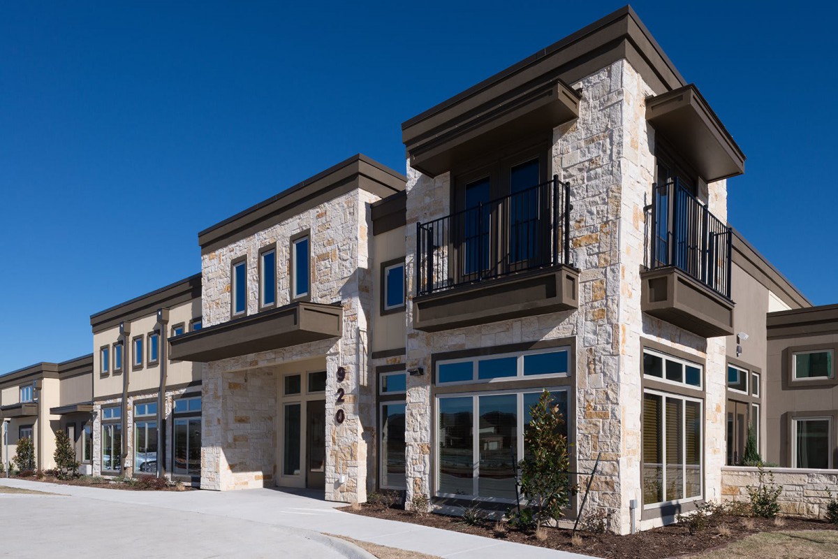 Modern commercial building with stone facade and large windows.
