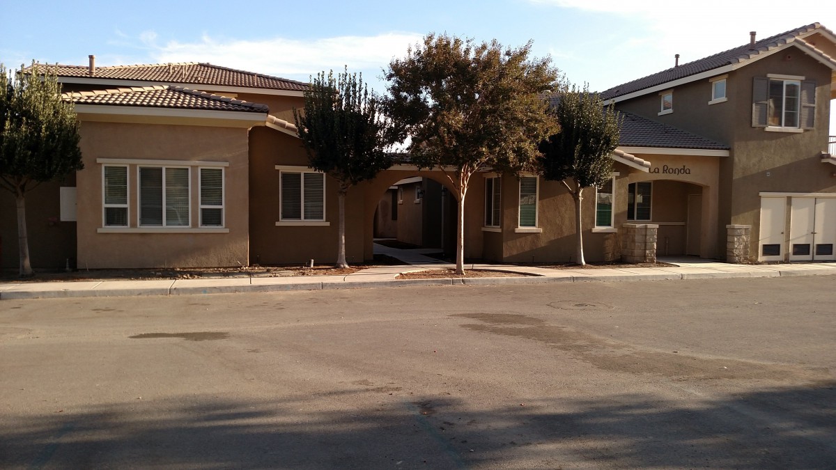A suburban residential building with trees and a clear sky.