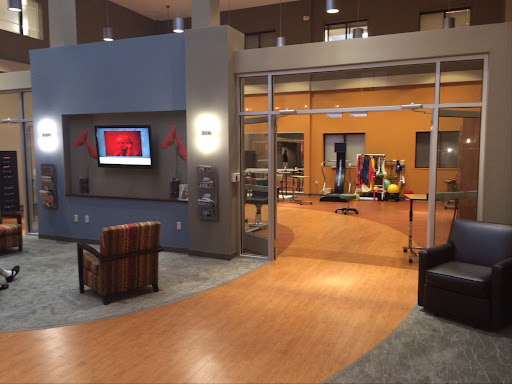 A modern lobby featuring a comfortable seating area, a television display, and an open design leading to another space.