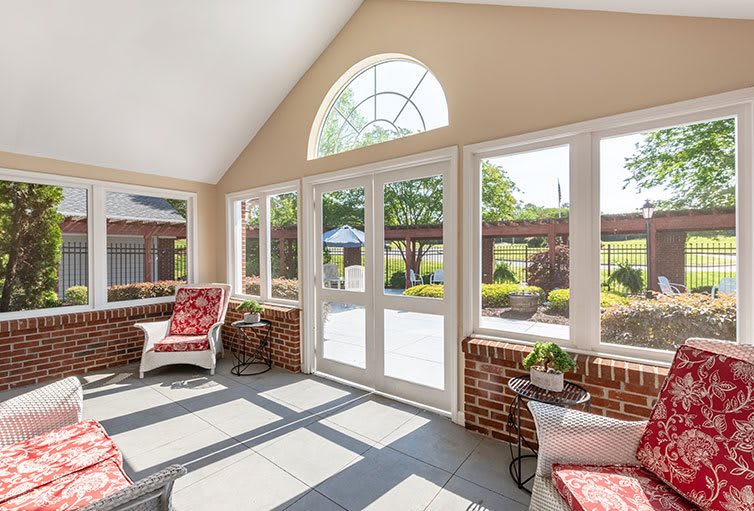A bright and inviting sunroom with large windows, brick walls, and comfortable patio furniture.
