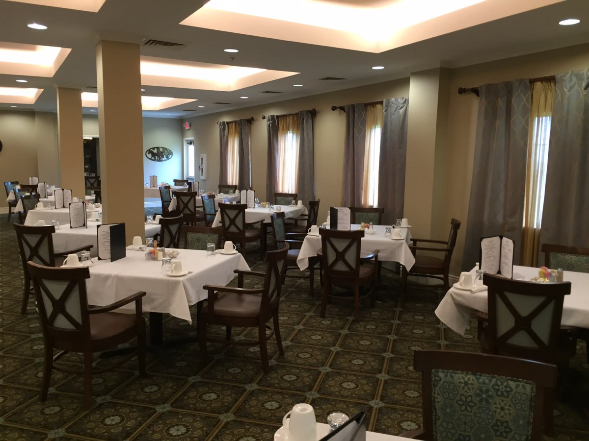 An empty restaurant dining room with neatly arranged tables and chairs.