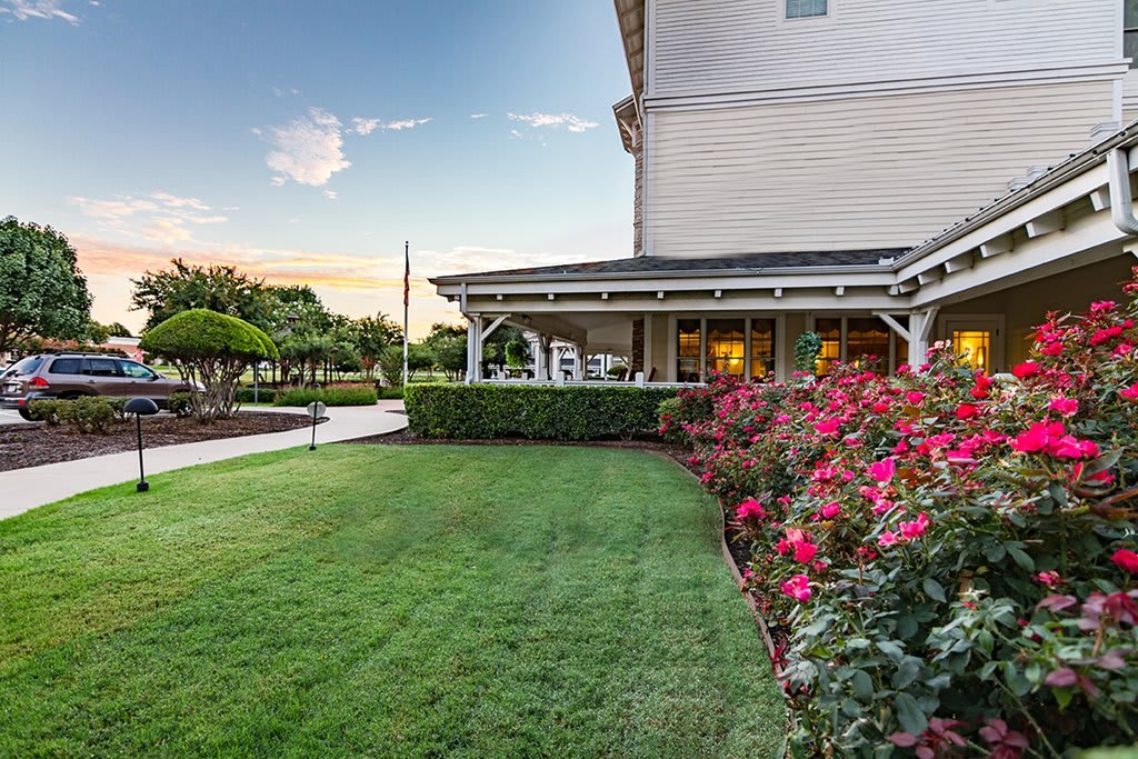 A beautiful backyard with a lush lawn, vibrant flower garden, and a cozy patio area.
