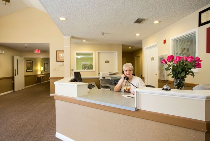A person sitting at a reception desk in an office interior.