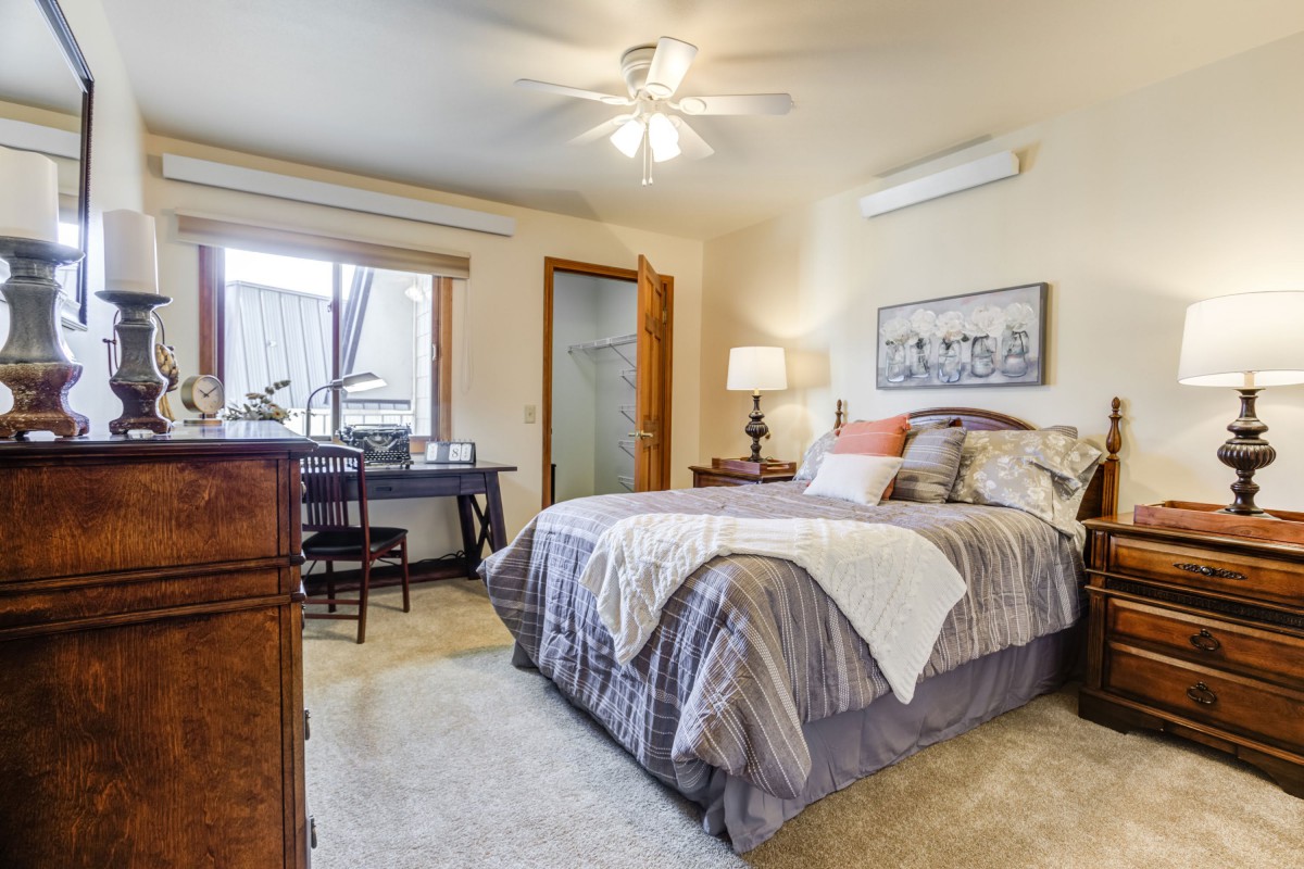 Cozy bedroom with a comfortable bed, desk, and natural light through the window.