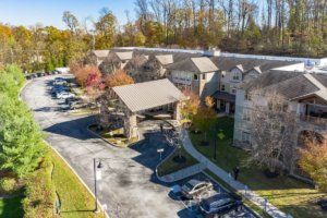 Aerial view of a large building surrounded by trees and a parking lot in autumn.