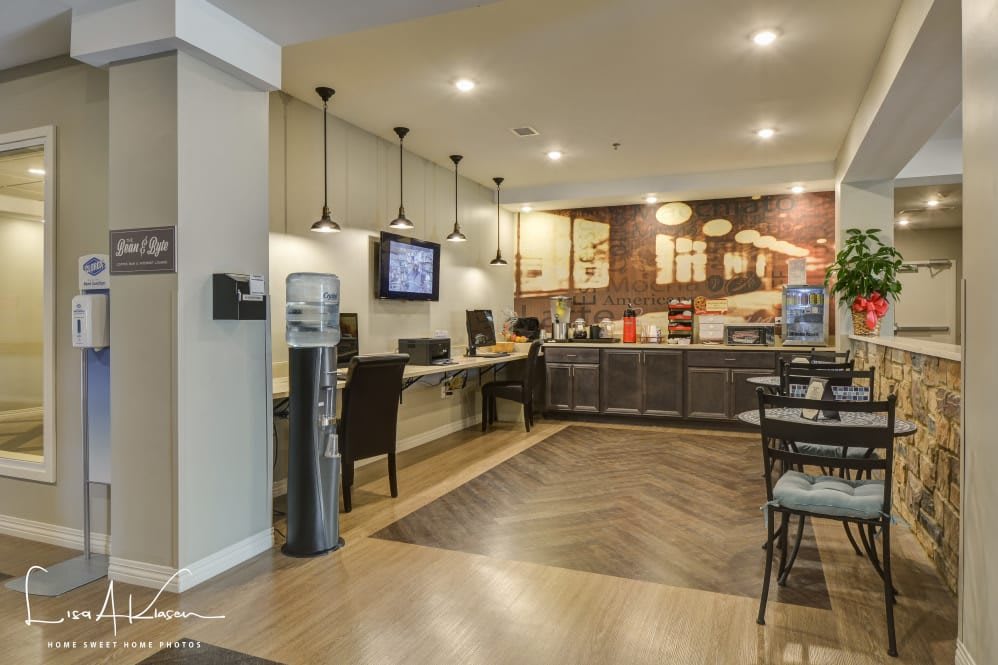 A modern cafe interior with seating, computers, and a water cooler.