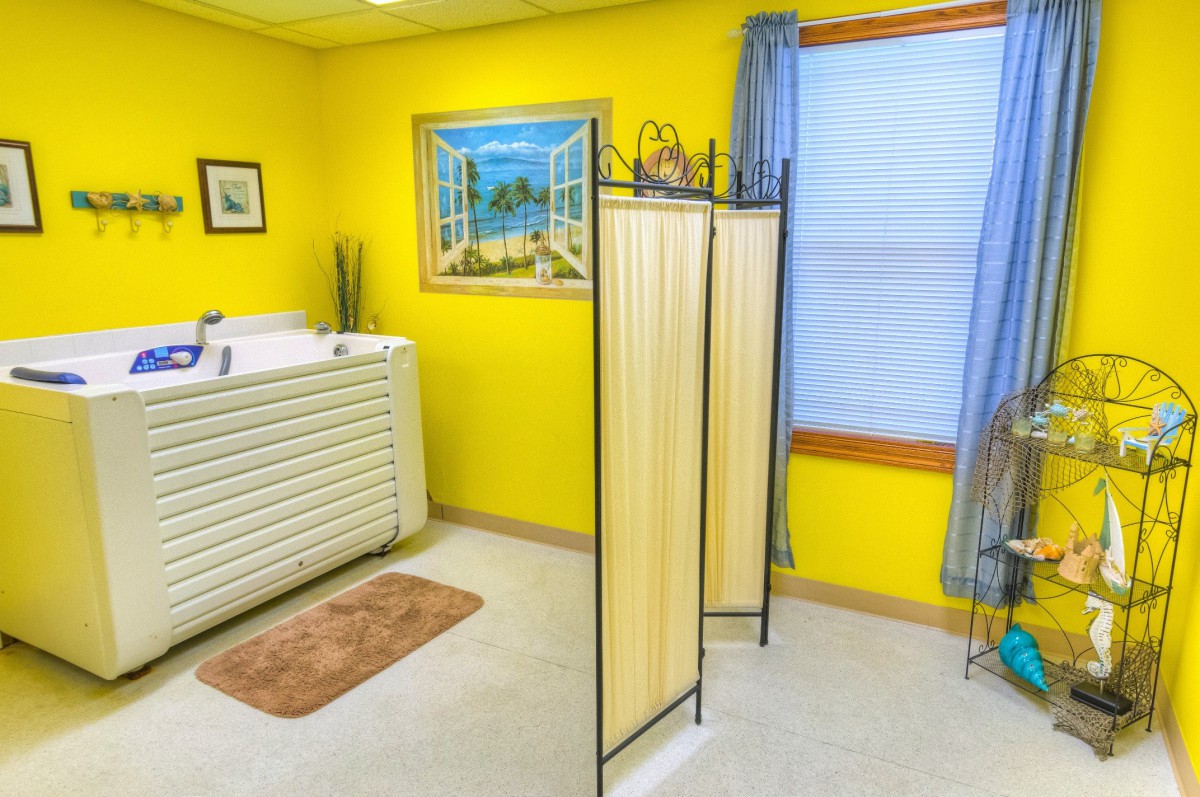 A brightly decorated room with yellow walls, featuring a bathtub and screen partition.