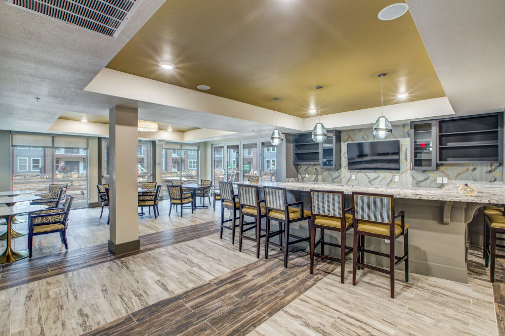 A modern kitchen and bar area with counter seating and pendant lighting.