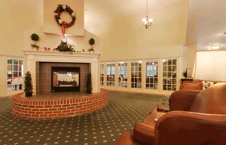 A cozy living room with a decorated fireplace and holiday wreath.