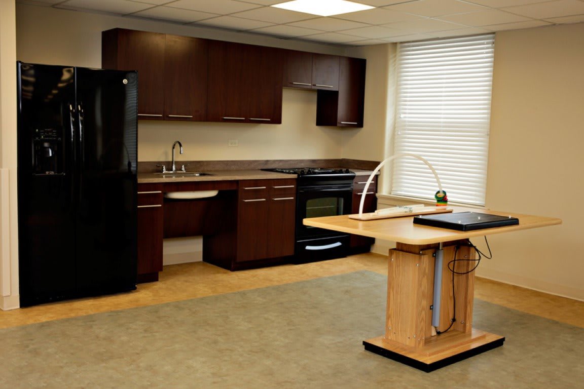 A modern kitchen interior featuring dark wood cabinets, a black refrigerator, and an integrated stove with a countertop island.