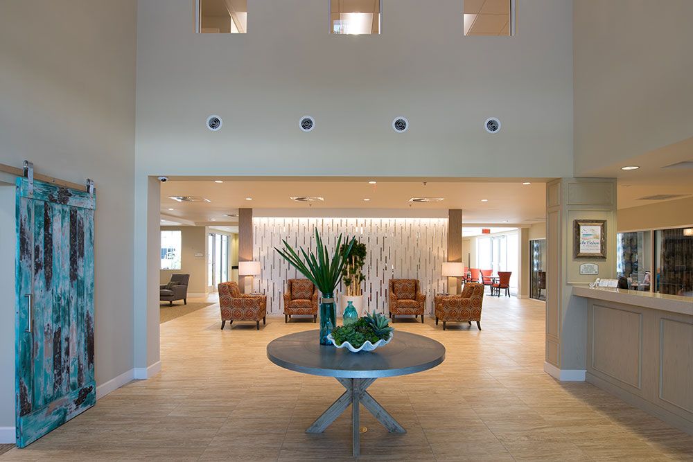 A spacious lobby with elegant decor, featuring a central table adorned with plants and a seating area in the background.