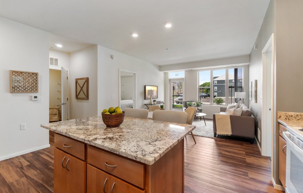 A modern open floor plan featuring a kitchen with a granite countertop and a connected living area.