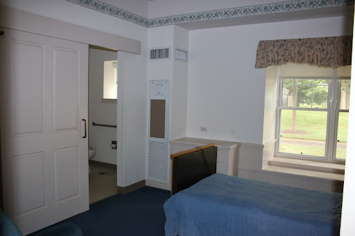 A spacious bedroom featuring blue bedding and a view of the outside through a window.