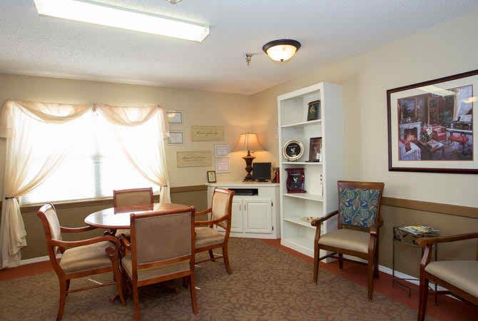 A cozy office meeting room with a round table and chairs, shelving, and a lamp.