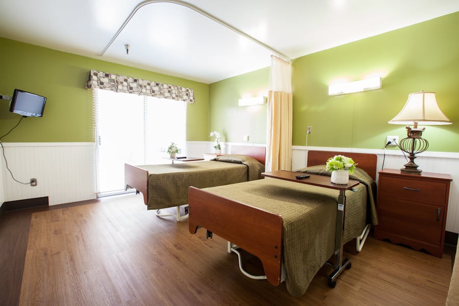 A well-lit hospital room with two patient beds and modern amenities.