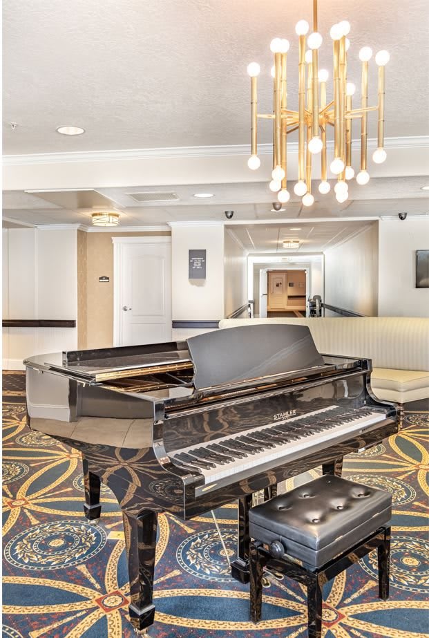 A luxurious hotel lobby featuring a grand piano and modern chandelier.