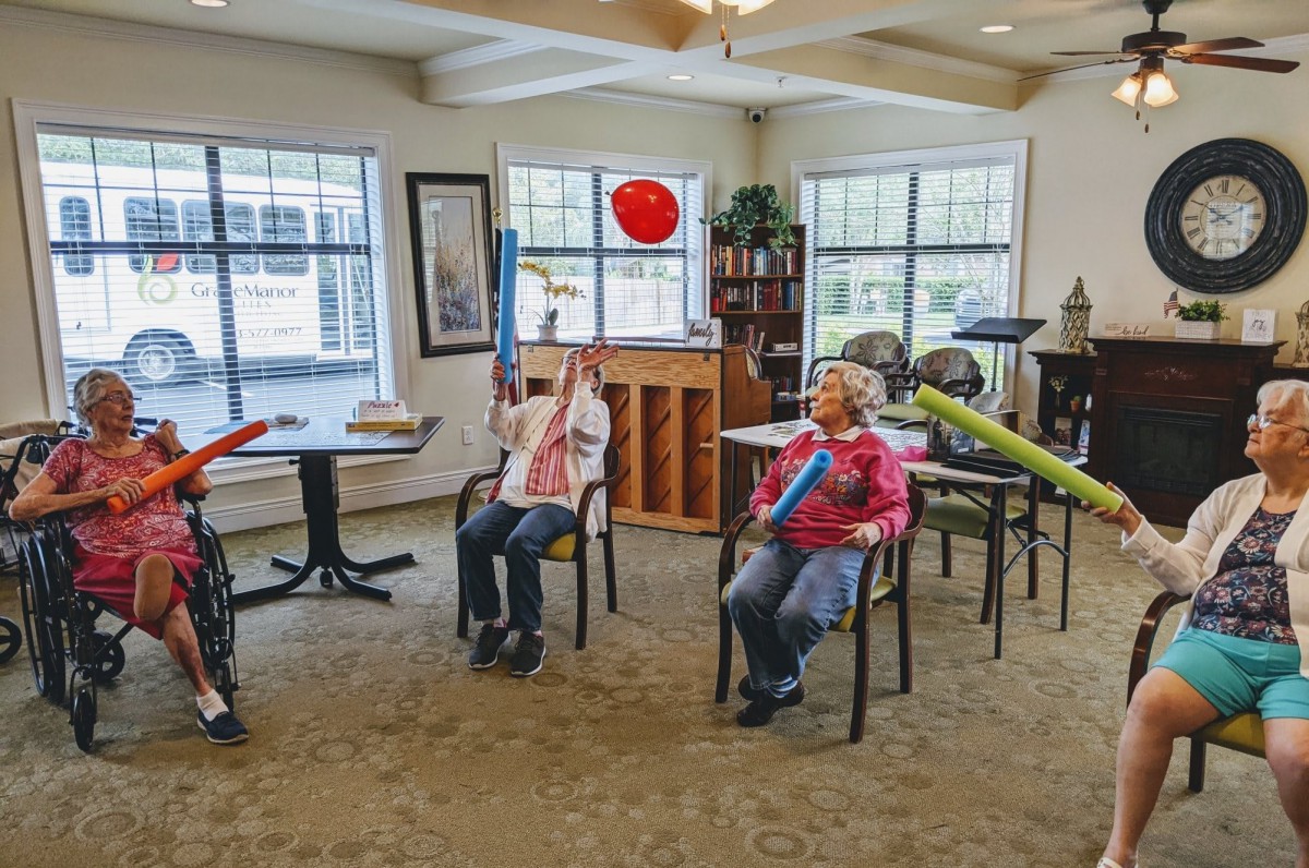 Seniors enjoying a music therapy session with boomwhackers in a recreation room.