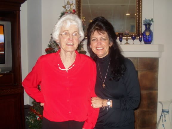 Two women posing together indoors, smiling at the camera.