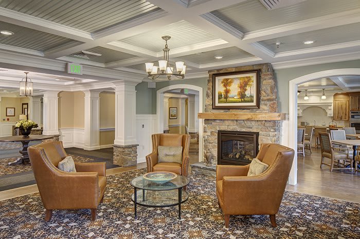A cozy living room with armchairs around a fireplace, featuring elegant decor and a chandelier.
