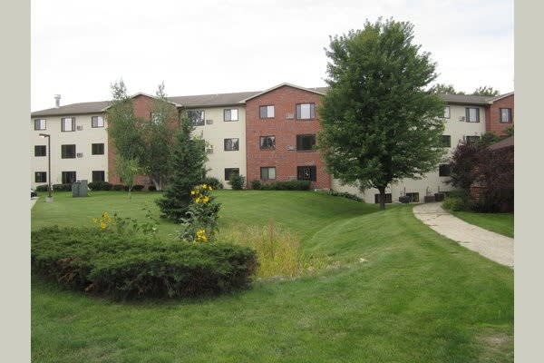 Image of a residential apartment building surrounded by well-maintained greenery and trees.