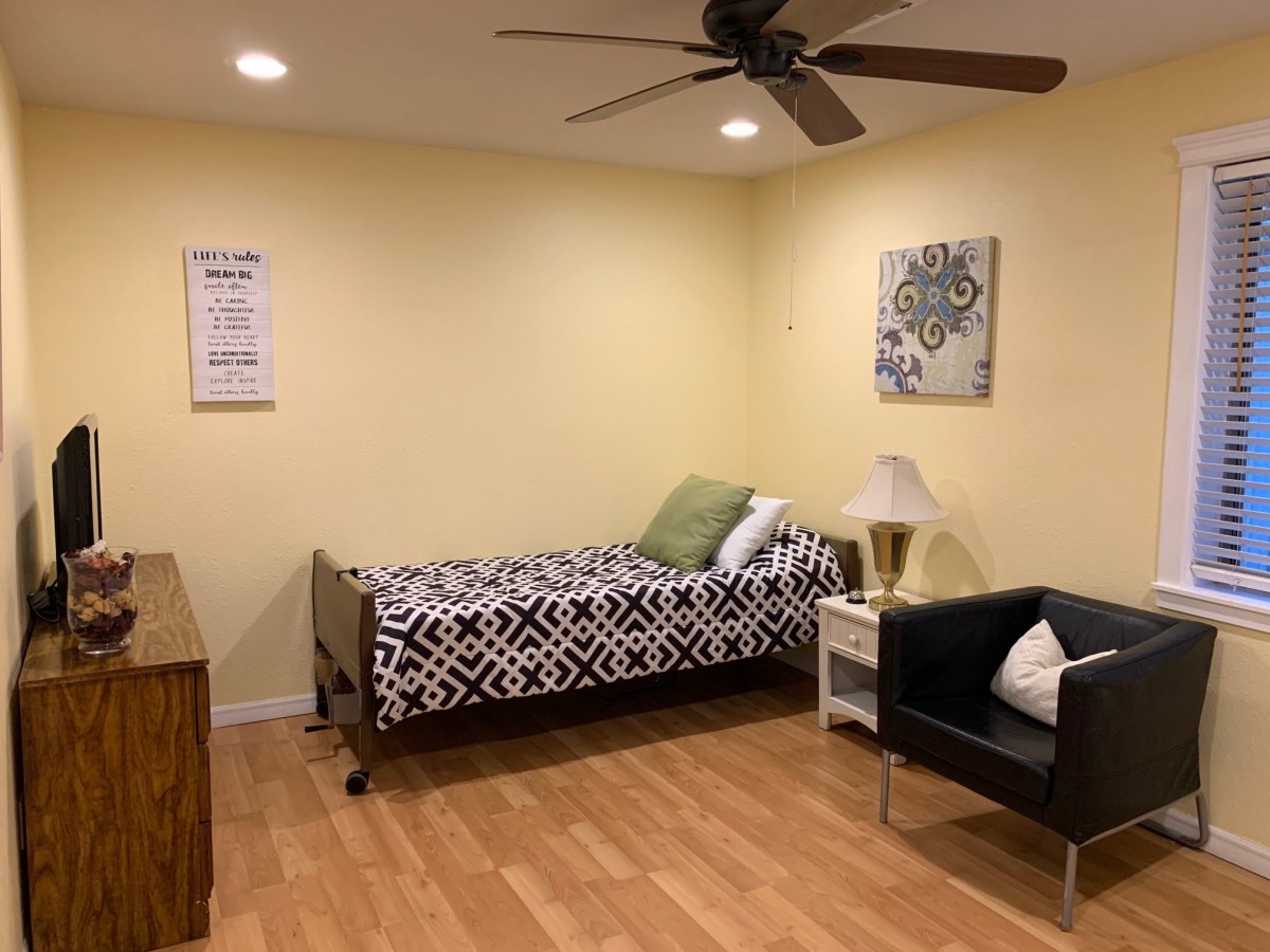 A tidy bedroom with a single bed, a chair, and decorative elements on the walls.