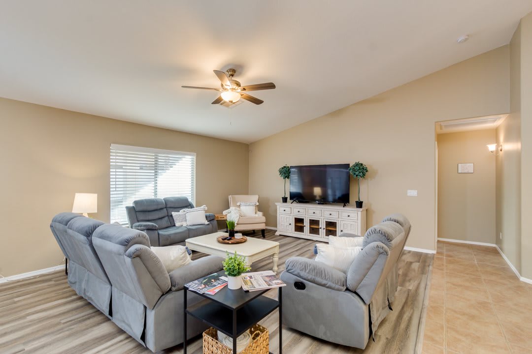 A modern living room with gray sofas, a large TV, and stylish decor.