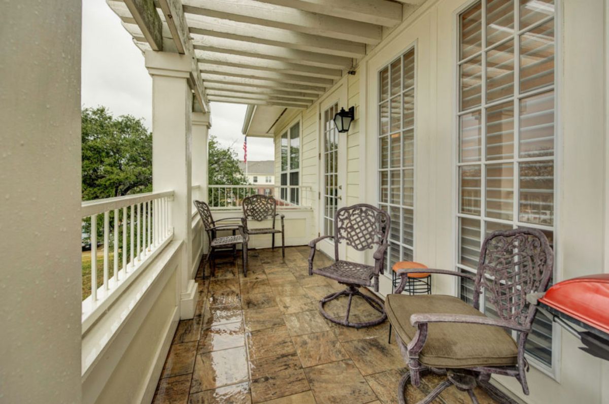A cozy covered balcony with outdoor seating and elegant railings.
